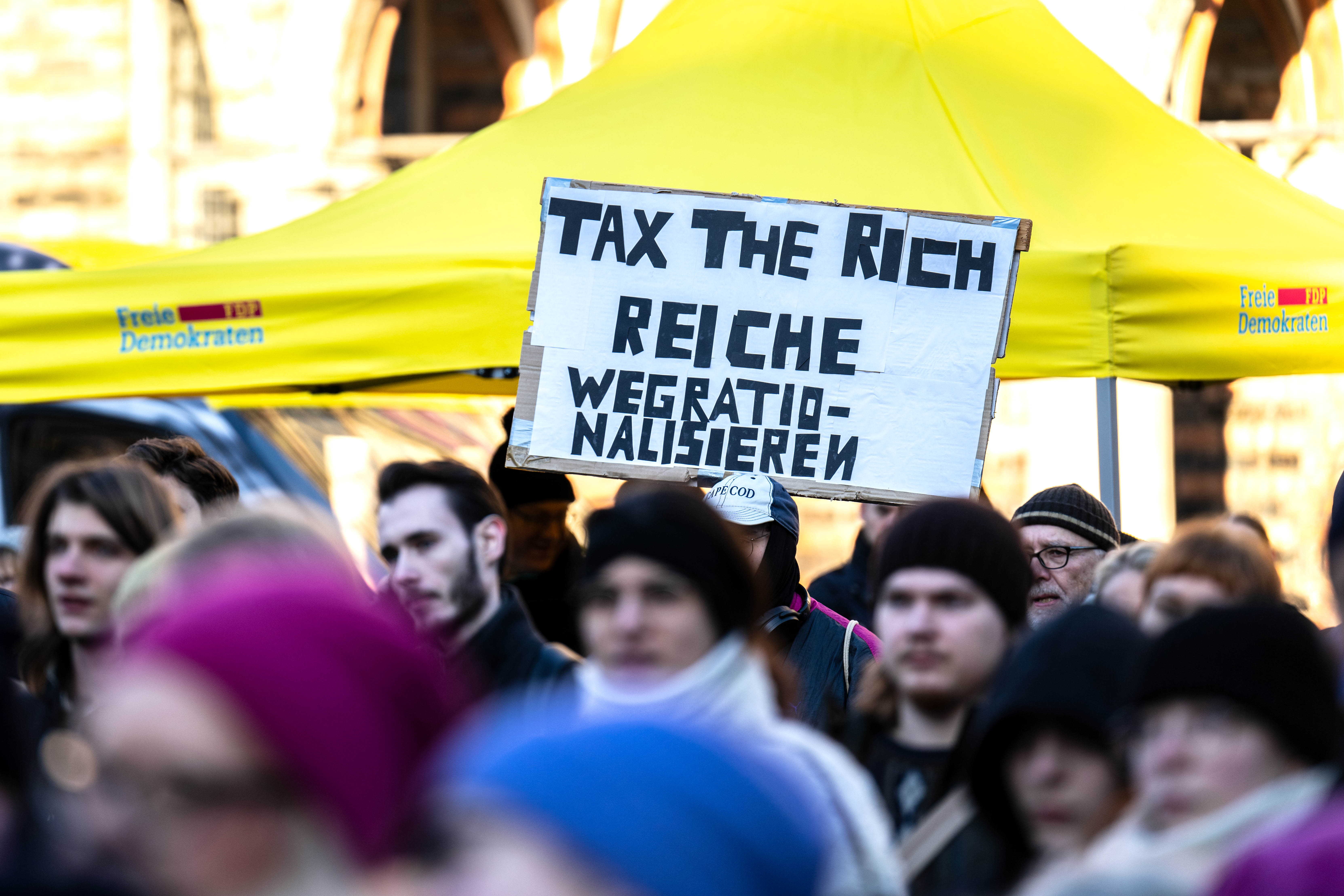 «Tax the Rich (Besteuerung der Reichen) - Reiche wegrationalisieren» steht auf einem Protestplakat bei einer Wahlkampfveranstaltung der FDP am 13.1.2025 auf dem Bremer Marktplatz. 